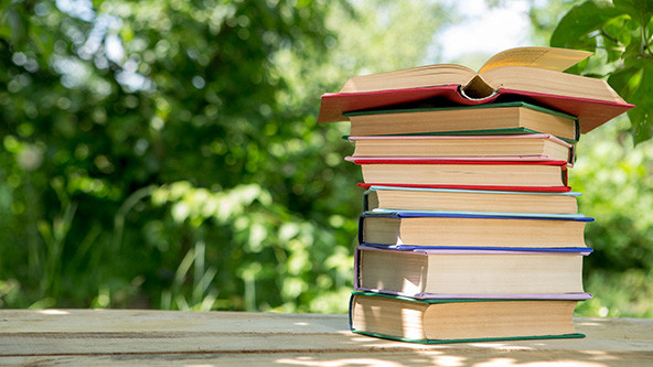 Stack of books on a wooden table in a garden