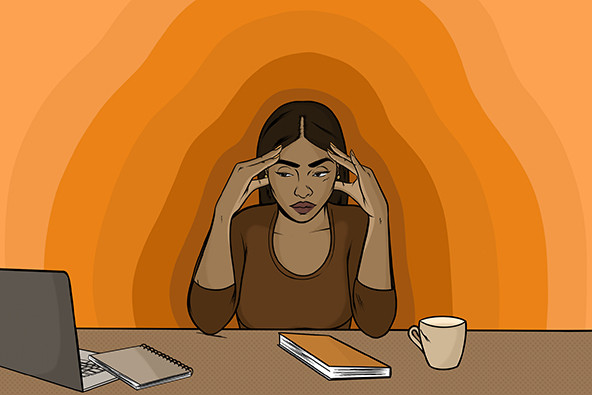 Brown-skinned woman sitting at desk with head in hands.