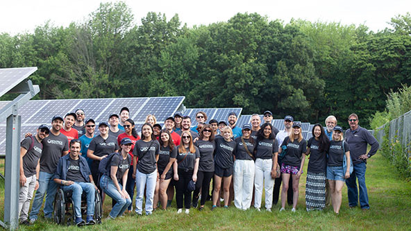 Group of people standing outdoors next to a solar farm