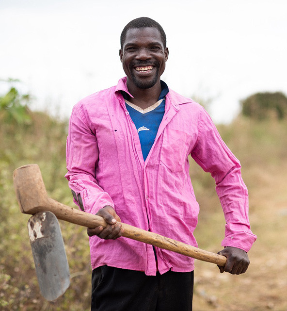 African farmer stands with a hoe in a field