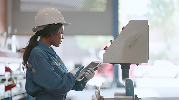 Expert female African American worker in manufacturing factory holding a tablet.