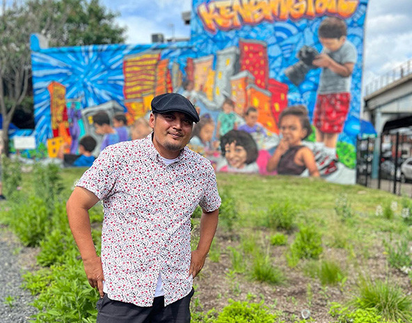 Man standing in front of a mural in a community garden.