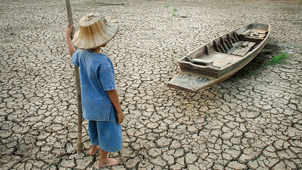 Child looking at boat on dried-up riverbed