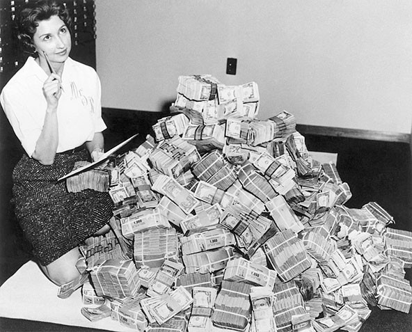 Black and white photo of a woman sitting next to a large pile of money