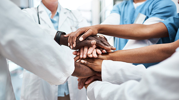 Closeup shot of a group of medical practitioners joining their hands together in a huddle