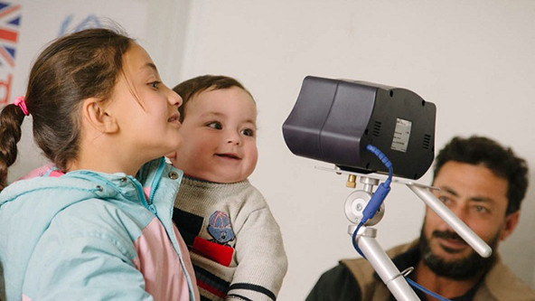 Two children looking into an iris scanner.