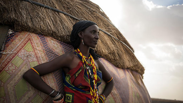 Kenyan woman standing outside her home.