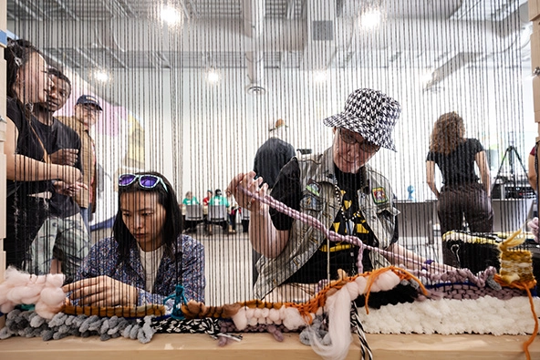 two weavers working on a loom