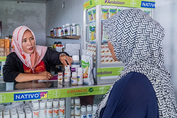Two women in head coverings speaking across a counter.