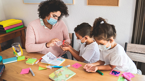 Teacher disinfect students hands with sanitizer gel.