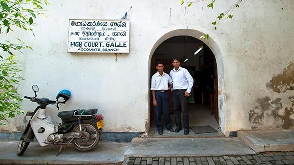 Two men standing outdoors next to an arched doorway