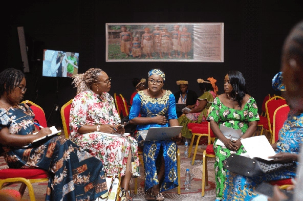 Women in traditional African dress sitting in a circle talking