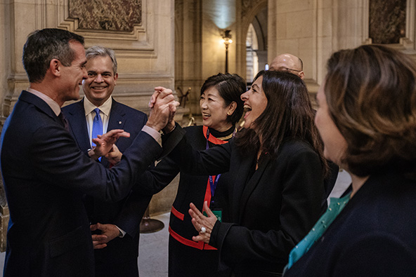 Two people in business clothes greet each other by clasping raised hands
