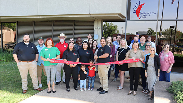 A crowd of people standing outside in front of a building at a ribbon cutting