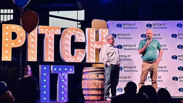 Two men on a stage next to the words 