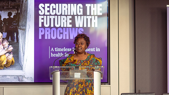 woman in traditional African dress speaking at a podium