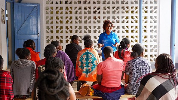 woman standing and speaking in front of a group of people