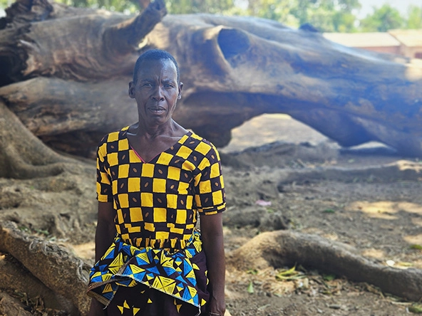 African woman in colorful dress sits outside