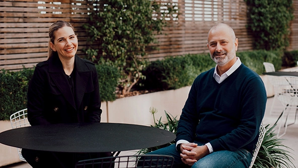 a man and a woman sitting at a table, facing the camera