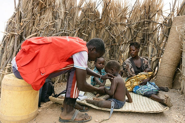 photo of health care worker checking a small child outdoors