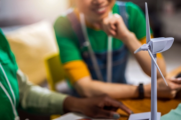 Young people sitting at a desk looking at a model wind turbine