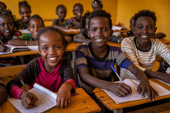 African children sitting at desks with notebooks in a school
