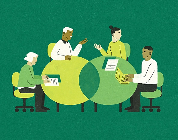 Older adults and younger adults working together at tables.