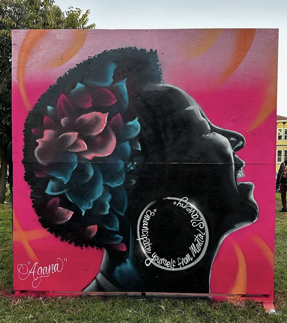 Black woman with head leaning back; mouth open singing; red, pink, and blue flowers in her hair
