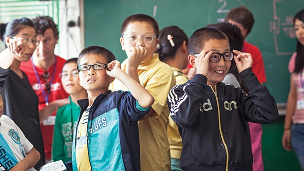 School children trying on glasses.