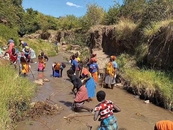 African women standing in a river in Kenya removing non-biodegradable waste from the water.