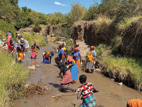 African women standing in a river in Kenya removing non-biodegradable waste from the water.