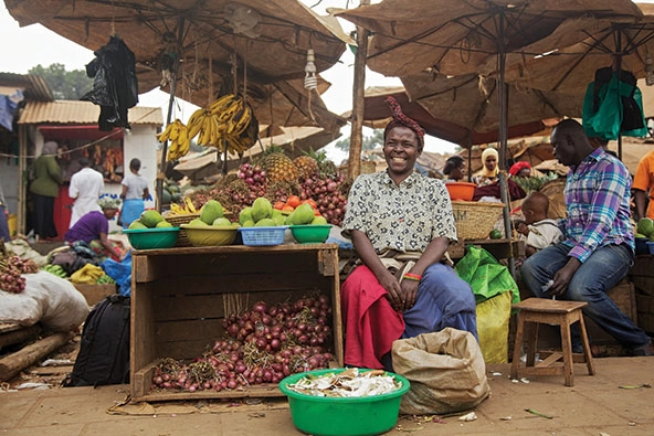 Woman sitting with a table of produce at a street market