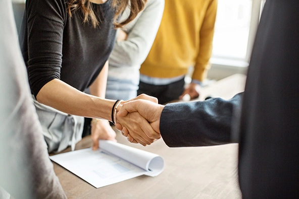 Cropped shot of businessman shaking hands with a person across the table.
