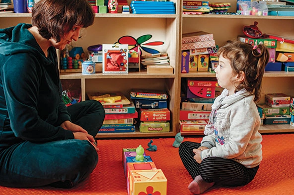 Woman sitting with young girl with toys in between them