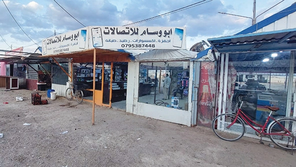 A storefront in a strip of stores next to a dirt road