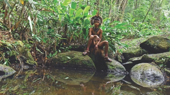 a man in Indigenous dress by a sacred pool in Brazil's Monte Pascoal National and Historic Park