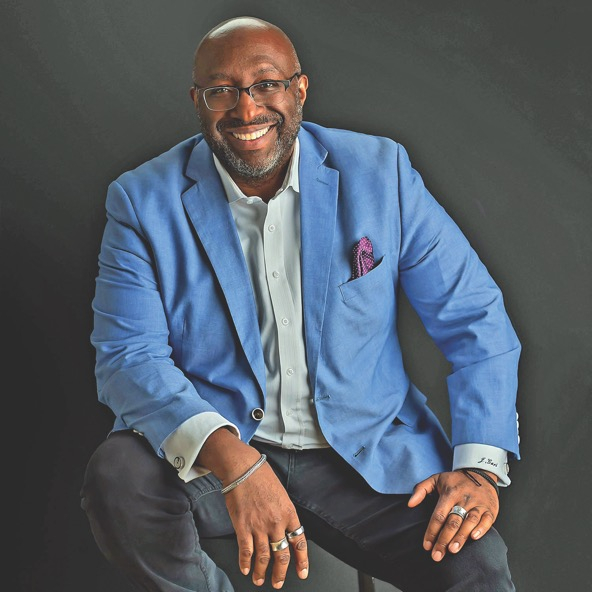 the CEO of SDA sitting on a chair and smiling for a portrait