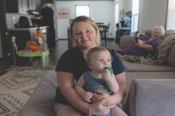 woman sitting in a home with her baby in her lap