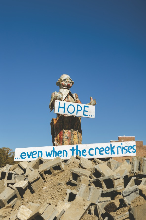 statue on a hilltop holding up a sign that reads 'hope'