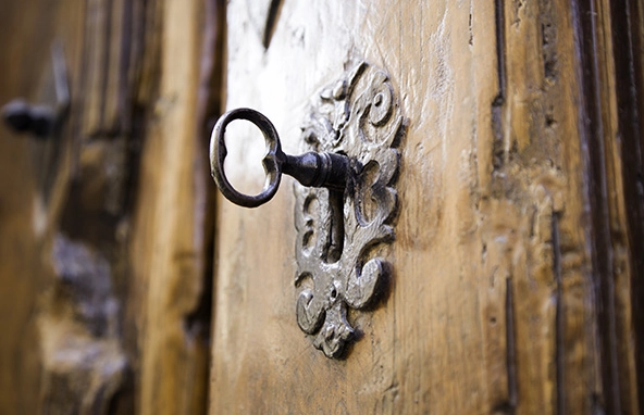 Antique key in ornate lock on wooden door
