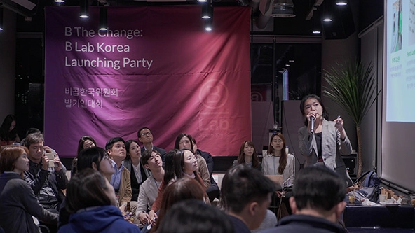 Image of a woman standing in front of a red and purple banner that reads 