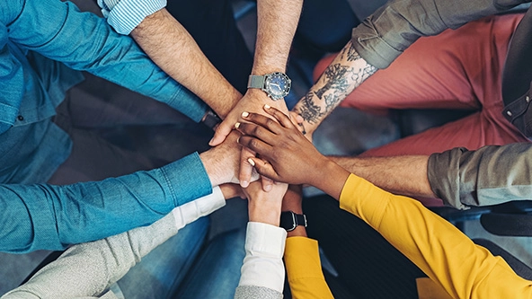 overhead shot of people standing in a circle and stacking hands