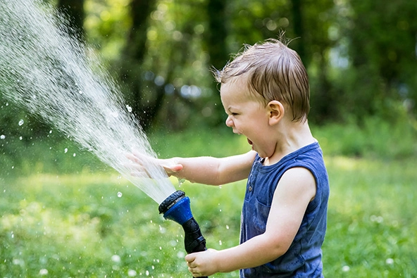toddler spraying a stream of water out of a hose
