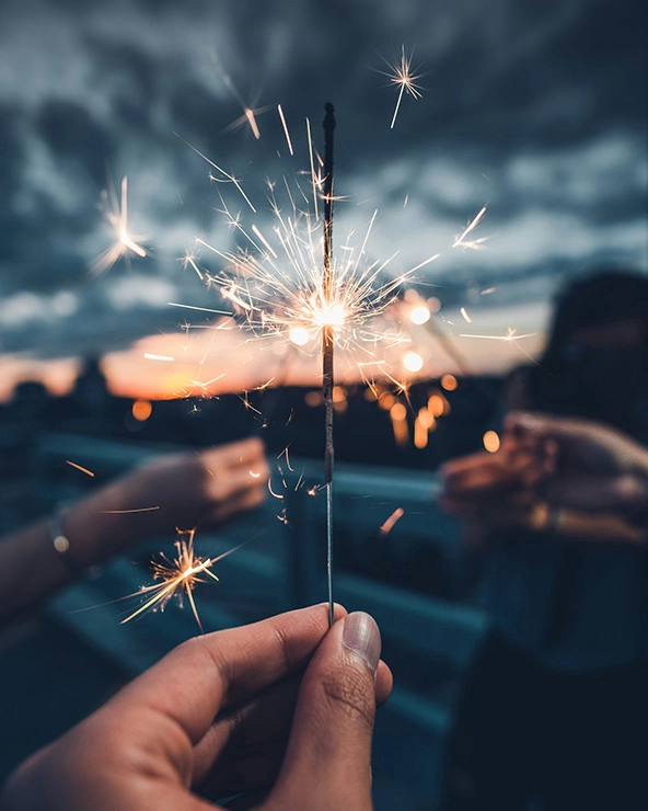 Hand holding a burning sparkle at dusk