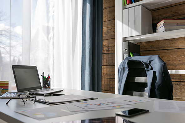 desk with laptop and empty chair with suit jacket hanging on the back