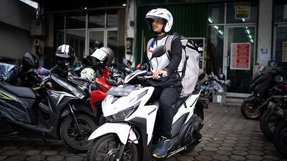 Photo of an Indonesian man riding a motorized scooter