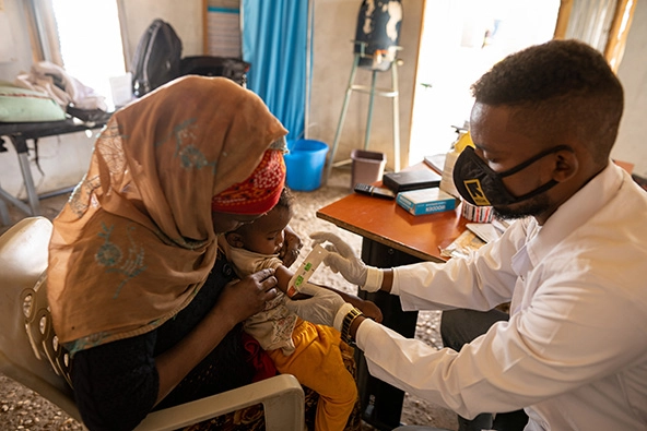 Mother holds infant while doctor performs an exam
