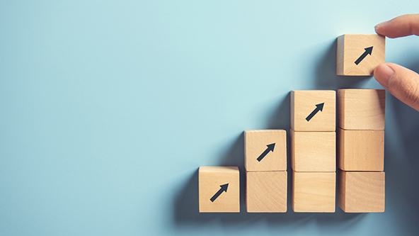 Hand arranging wood blocks with arrows stacking as step stair