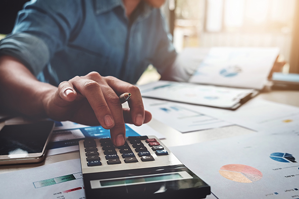 person using a calculator with budget and loan papers in office