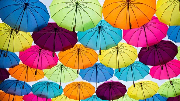 Open umbrellas that are different colors hanging from the sky